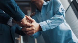 Two men in business attire shaking hands - representing the blog Moving From Transactions to Relationships