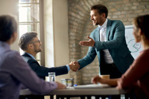 Trust-2 - Legacy Two businessmen shaking hands over a conference table