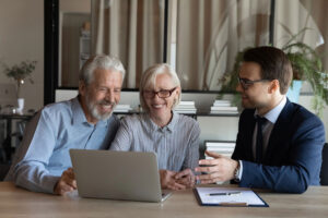 Happy Older Clients talking to a trusted advisor behind a computer.